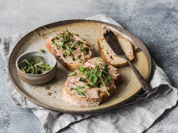 два тоста утка с черносливом rillettes паштет на белом хлебе с ростками и различными семенами на винтажной тарелке на сером фоне. - duck meat meat white meat food стоковые фото и изображения