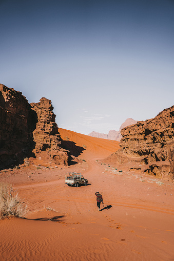 Scenic view of young Caucasian man near the SUV in Wadi Rum desert  at sunset