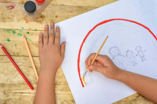 istock Children's hands paint a drawing with a brush and paints. Top view 1127572262