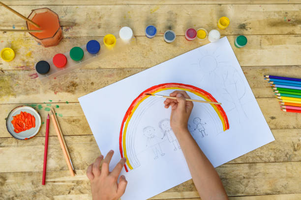 istock Children's hands paint a drawing with a brush and paints. Top view 1127572275