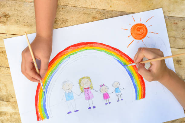 istock Two children's hands draw a drawing with a brush and paints. Top 1127572276