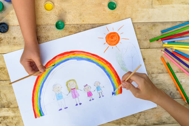 istock Two children's hands draw a drawing with a brush and paints. Top 1127572279