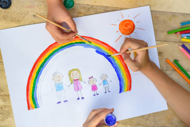 istock Two children's hands draw a drawing with a brush and paints. Top 1127572292
