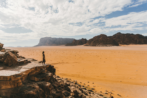 Young Caucasian woman  looking at  Wadi Rum desert  from above at sunset