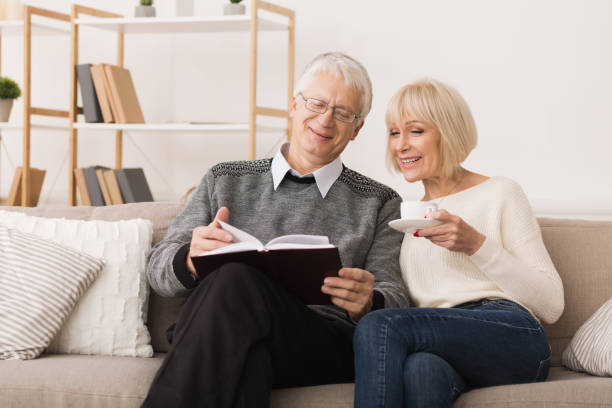 istock Senior couple reading book on couch at home 1127572912