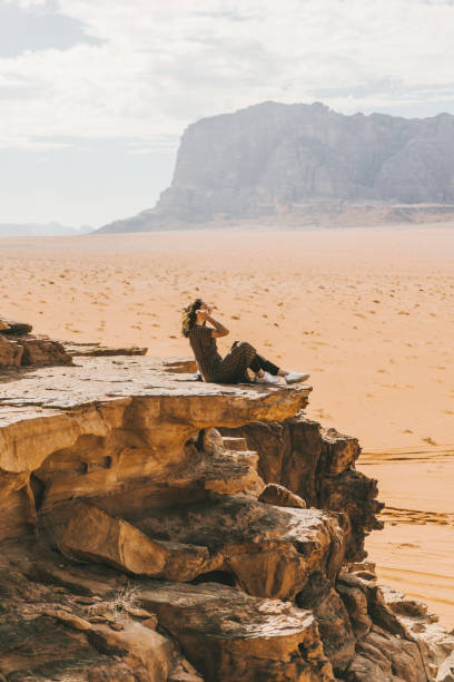 istock Woman sitting and  looking at  Wadi Rum desert from rock 1127573251
