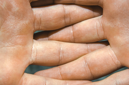 Men's caucasian hairy arms intertwined in the fight with fingers. Inner part of hand.