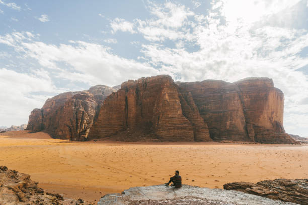 istock Man sitting and  looking at  Wadi Rum desert from rock 1127576052