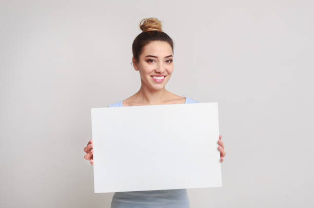 istock Your text here. Pretty woman holding empty blank board 1127578524