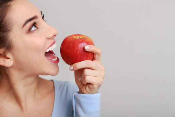 istock Healthy eating. Woman biting red apple over background 1127578527