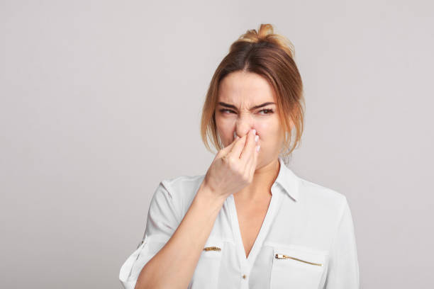 Woman closing nose because of bad smell Woman closing nose because of bad smell on grey studio background unpleasant smell stock pictures, royalty-free photos & images