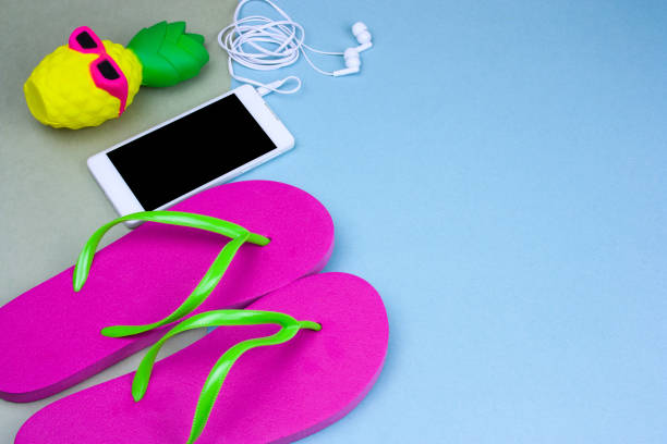 top view flat lay cute pineapple in sunglasses, smartphone and pink flip flops
