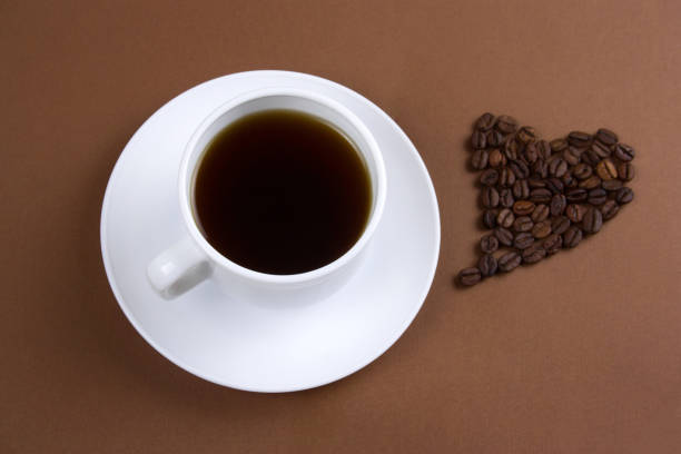 istock black coffee cup and heart with coffee beans on brown background 1127581293