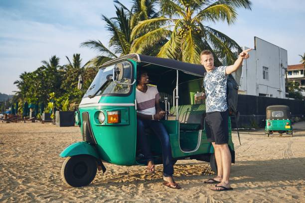 Traveling by tuk tuk taxi Tuk tuk driver with passenger against sand beach in Sri Lanka. taxi sri lanka stock pictures, royalty-free photos & images