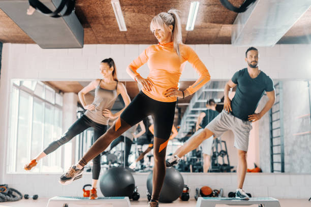 grupa przyjaciół robi ćwiczenia fitness dla nóg w siłowni. w tle ich odbicie lustrzane. - aerobics zdjęcia i obrazy z banku zdjęć