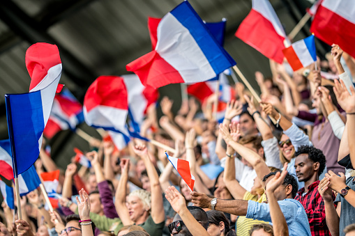 Crowds of French sports fans waving their flags on a stadium.