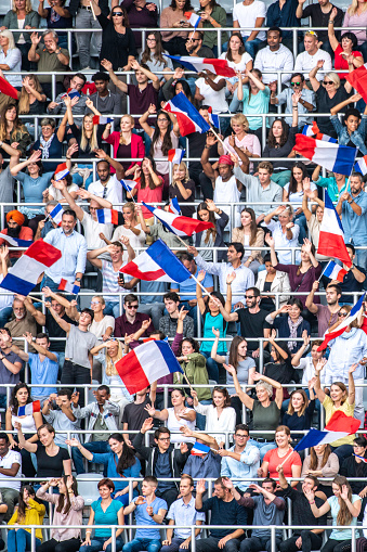Vertical photo of French sports fans waving their flags on a stadium.
