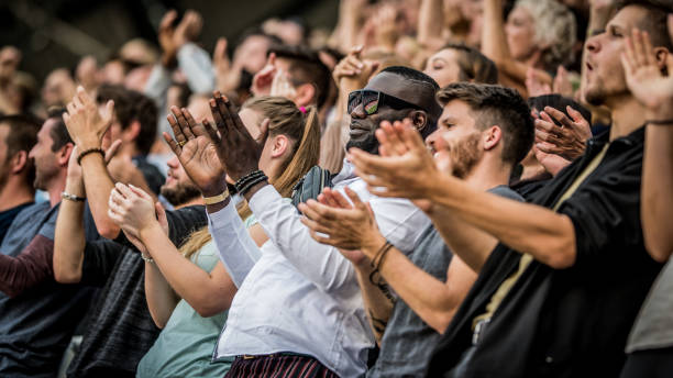 istock Multi-ethnic group of people standing and clapping at a sports event 1127582496