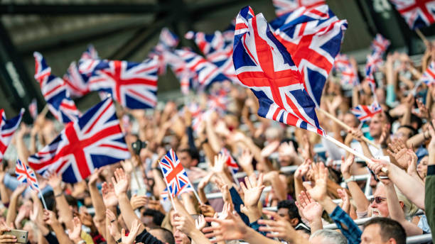 Great Britain fans waving flags on a stadium Large group of Great Britain fans waving their flags while cheering on stadium stands. fen photos stock pictures, royalty-free photos & images
