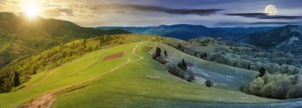 panorama of night and day time change above countryside. path down the grassy rural hills rolling in to the distance. ridge beneath an overcast sky with sun and moon in spring