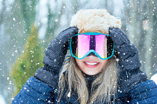 Portrait of Female Snowboarder with ski goggles in nature