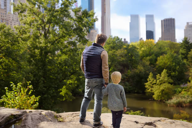 l'uomo e il suo affascinante figlio piccolo ammirano i panorami a central park, new york - autumn park central park lake foto e immagini stock