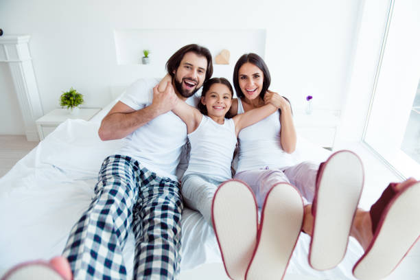 istock Nice cute adorable lovely attractive cheerful cheery funky people lying on bed enjoying life rejoicing in modern white light interior room 1127586607