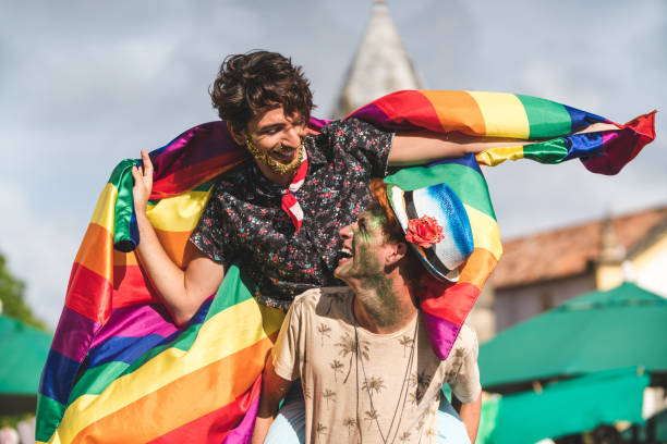 bandiera coppia omosessuale con bandiera arcobaleno - homosexual gay man symbol homosexual couple foto e immagini stock