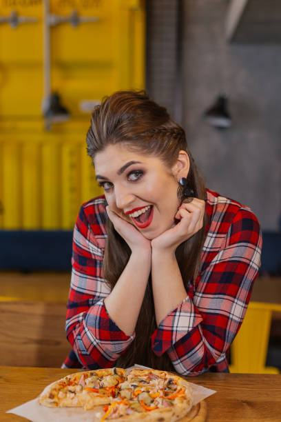 istock Girl sitting at a table with a pizza in a cafe 1127590379