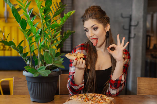 istock Girl sitting at a table with a pizza in a cafe 1127591292