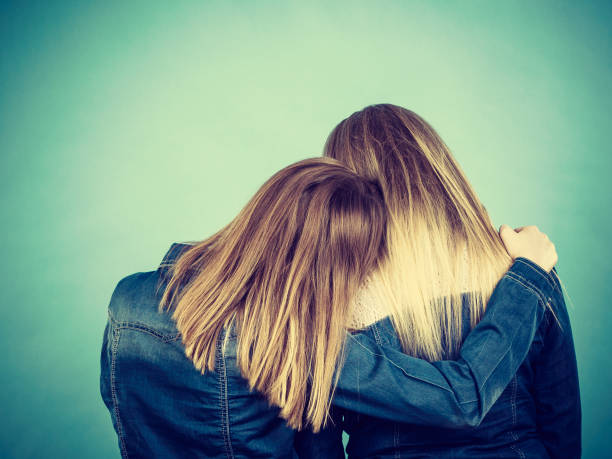 Back view of two unrecognizable blonde women hugging each other. Friendship, family love concept.