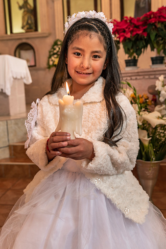 Portrait of a girl with candle celebrating her holy communion