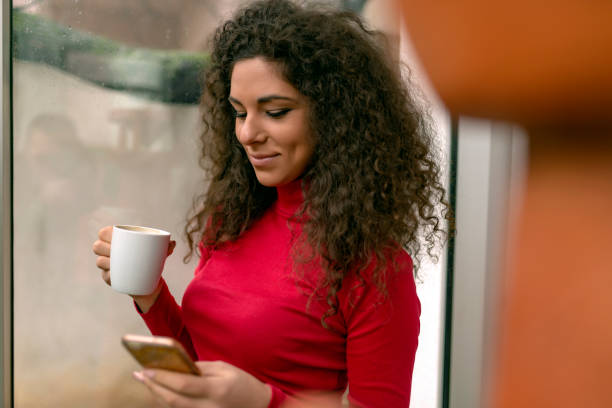 istock Pretty young woman enjoying coffee while using a smart phone 1127598038