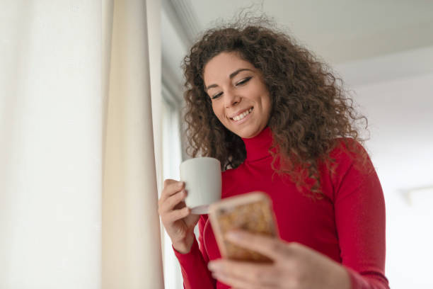 istock Pretty young woman enjoying coffee while using a smart phone 1127598944