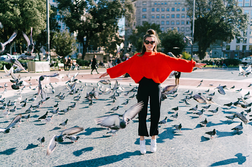 Girl in Barcelona jumping among the pigeons
