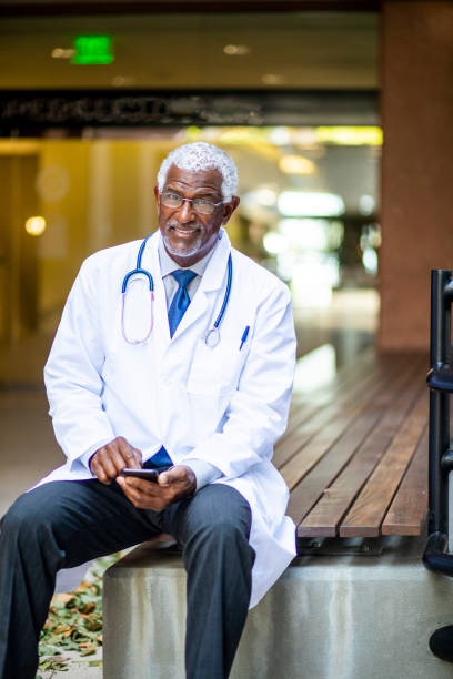 istock Senior Black Doctor Texting in front of Hospital 1127601106