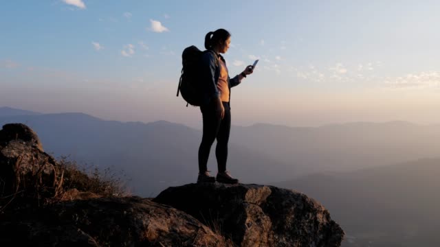 Hiker woman using mobile phone for take a photo on the top of mountain in sunset time , dolly movement , slow motion 4K(UHD)