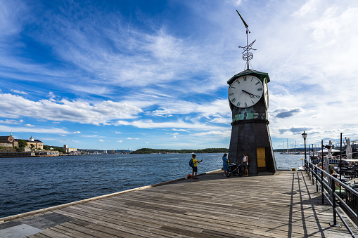 Aker Brygge Clock Tower on the wooden, pier overlooking Oslo fjord. Oslo, Norway, August 2018