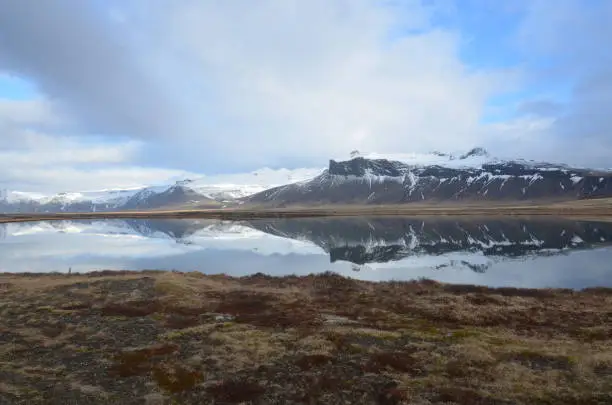 Iceland's Rhyolite snow covered mountains reflecting in water.