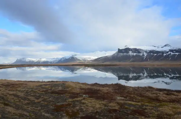 Water reflection of Icelandic snow-capped mountains.