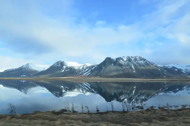 Beautifu snow covered mountains in Iceland reflecting in a pool of water.