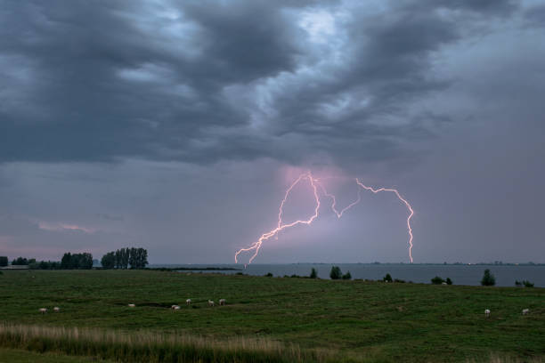 lightning strikes várias vezes na água abaixo de um céu dramático - agricultural equipment flash - fotografias e filmes do acervo