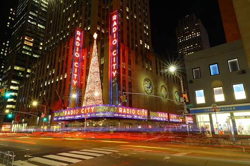 New York, New York - December 9, 2018: A long exposure of travel heading up Sixth Ave. past Radio City Music Hall in New York, New York. (Gordon Donovan/iStockphoto via Getty Images)