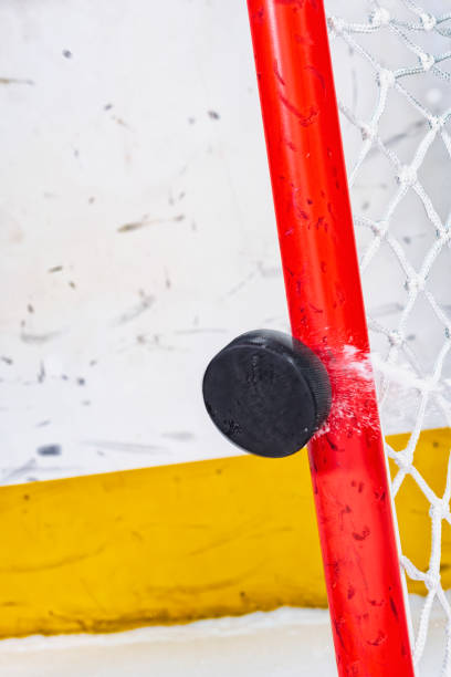 close-up of an ice hockey puck hitting the goal pipe as snow flies off - ice hockey hockey puck playing shooting at goal imagens e fotografias de stock