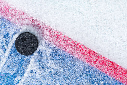 Mirando hacia abajo en un duende malicioso del hockey sobre hielo sentado en el borde de la 