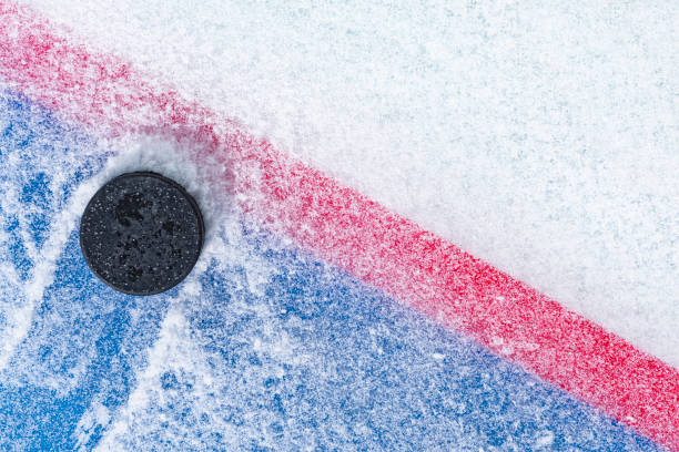 Looking down on a ice hockey puck sitting on the edge of the “Goal Line” of the goal crease stock photo
