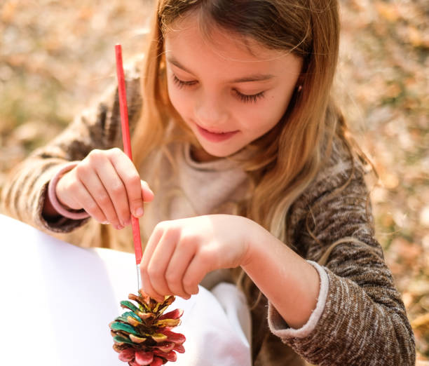 istock girl painting pinecone 1127622704