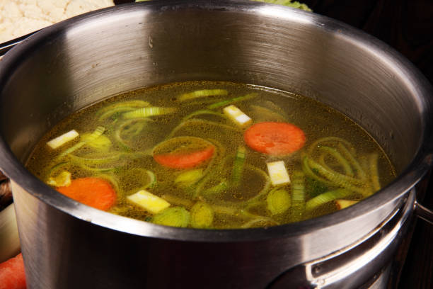 istock Broth with carrots, onions various fresh vegetables in a pot - colorful fresh clear spring soup. Rural kitchen scenery vegetarian bouillon or stock 1127623038