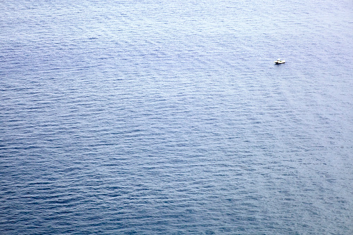 Seascape, blue water surface and fishing boat. Full frame image suitable for background purposes. Madeira island, Portugal.