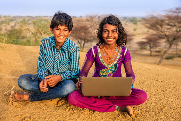 istock Happy Indian children using laptop, desert village, India 1127625303